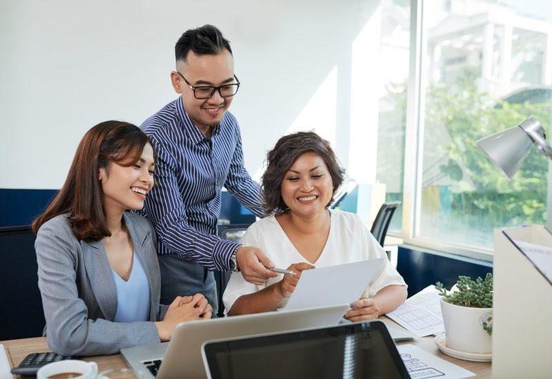Team of cheerful managers discussing business document at meeting